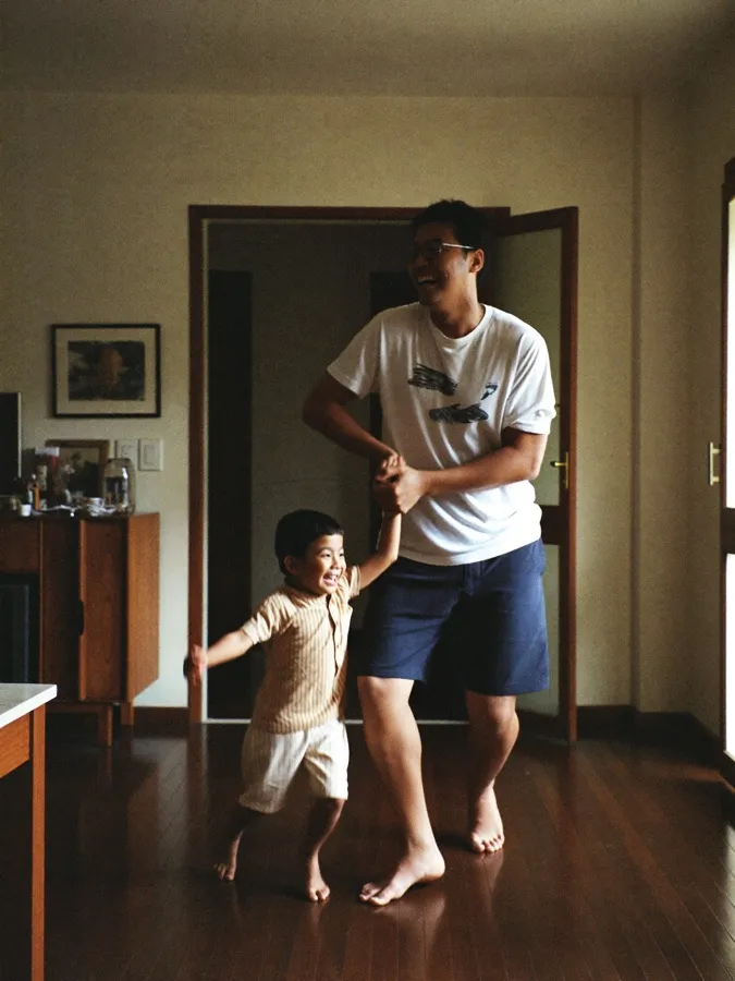 Pai e filho dançando descalços na sala de casa